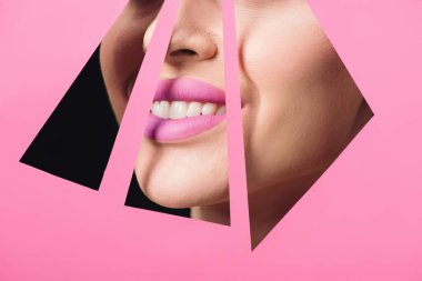 Cropped view of woman with pink lips smiling across triangular holes in paper on black background clipart