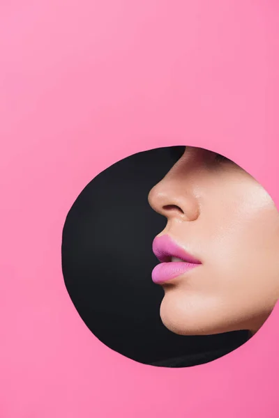 黑色纸片圆形孔中粉红唇女性面容的局部视图 — 图库照片