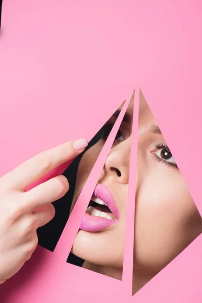 開いた口とピンクの唇を持つ女性は三角形の穴を渡って見て 手で紙に触れる黒の背景 — ストック写真