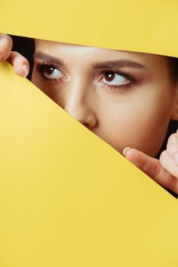 Woman looking away across hole and touching yellow paper with fingers clipart