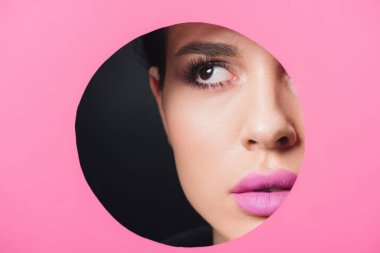 Güzel bir kız, dumanlı gözleri ve pembe dudakları var. Siyah kağıda sarılmış yuvarlak bir delikten başka tarafa bakıyor. 