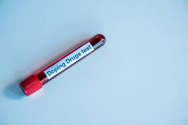 top view of test tube with blood sample and doping drugs test lettering on blue  clipart