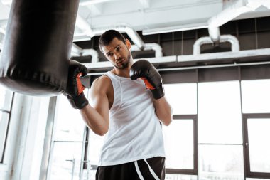 Boks eldivenli, kum torbasıyla antrenman yapan bir sporcunun seçici odağı.  