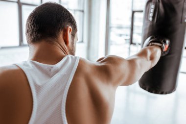 Boks eldivenli sporcunun kum torbasıyla antrenman yaptığı arka plan görüntüsü.  