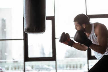 Kum torbasıyla boks eldivenli yakışıklı sporcunun yan görünüşü  
