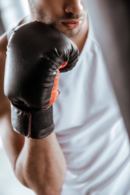 Spor merkezinde siyah boks eldiveni giymiş sporcu görüntüsü. 