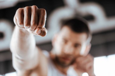 selective focus of fighter with clenched fist training in sports center  clipart