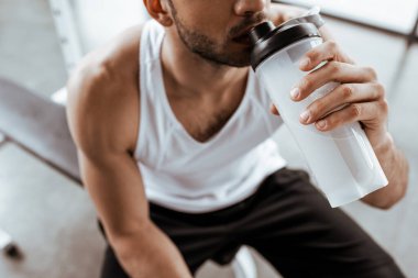 Sporcunun elinde spor şişesi tutarken protein milkshake 'i içtiği görüntüler. 
