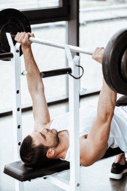 Spor salonunda halterle çalışan yakışıklı bir sporcu. 