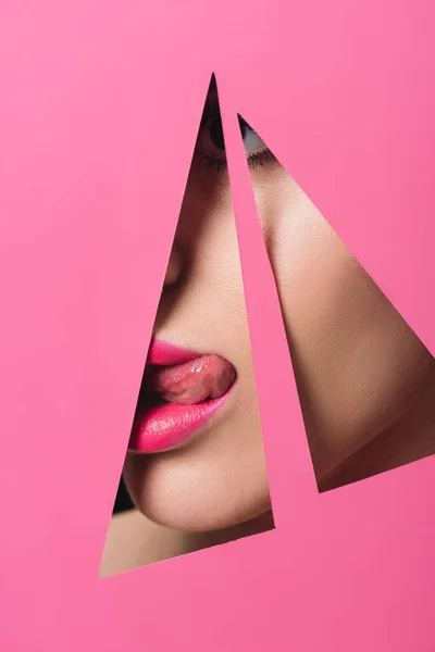 粉红嘴唇的妇女伸出舌头穿过纸孔 — 图库照片