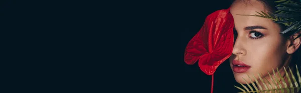 Портрет Привабливої Жінки Дивлячись Камеру Закриваючи Обличчя Антуріумом Ізольованим Чорному — стокове фото