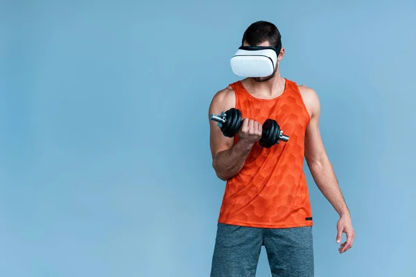 在虚拟现实耳机中工作的运动员 带着蓝色孤立的哑铃 — 图库照片