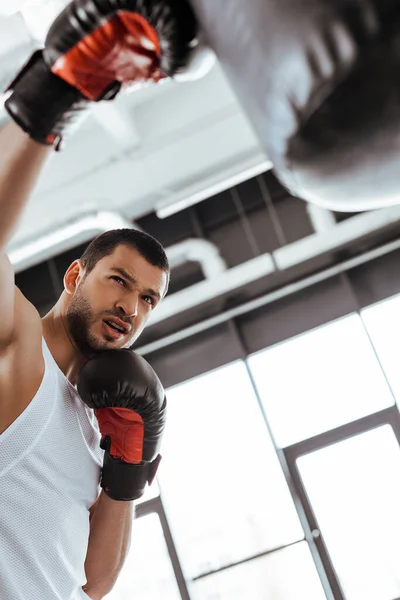 パンチングバッグで運動するボクシンググローブのスポーツマンの選択的な焦点 — ストック写真