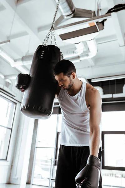 パンチバッグの近くに立つボクシンググローブの疲れきったスポーツマン — ストック写真