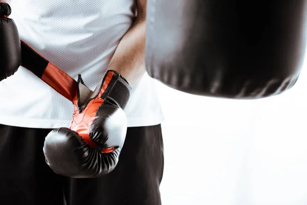 スポーツセンターで黒のボクシンググローブに触れるスポーツマンのクロップドビュー — ストック写真