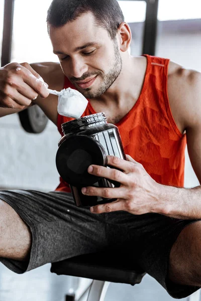 快乐的运动员拿着罐子 看着装有蛋白质粉的勺子 — 图库照片