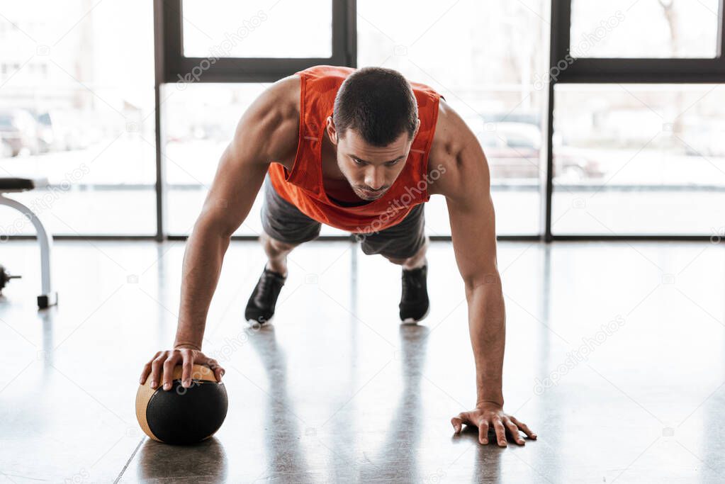 handsome sportsman doing plank exercising with ball 