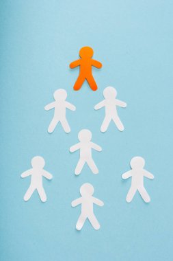 Flat lay with unique orange decorative man among white on blue background clipart