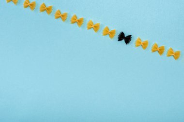 Top view of black pasta among yellow on blue background clipart