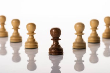 Selective focus of brown pawn with another on white background clipart