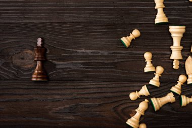 Top view of unique brown king with white chess pieces on wooden background clipart
