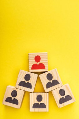 Top view of wooden cubes with red painted man among another on yellow background clipart