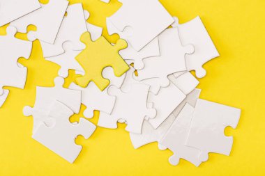 Top view of unique piece of puzzle among another on yellow clipart