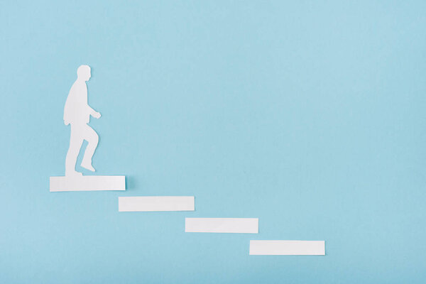 Top view of paper man on career ladder on blue background