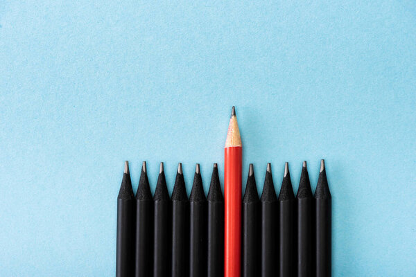 Top view of red pencil among black on blue background