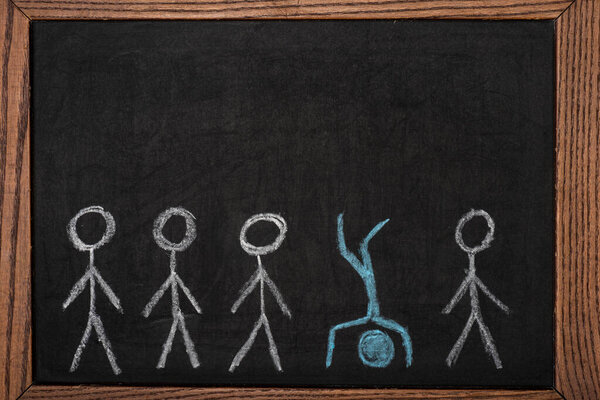 Уникальный нарисованный мужчина среди других на черной доске в деревянном каркасе
