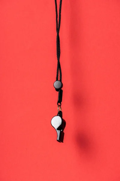 stock image Black whistle on rope on red background