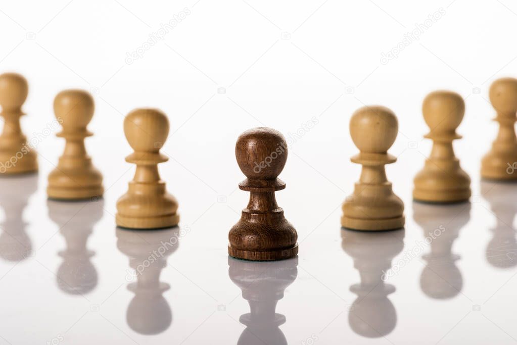 Selective focus of brown pawn with another on white background