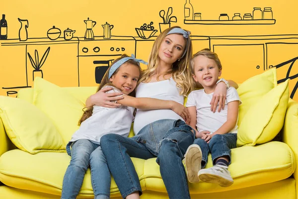 快乐的孕妇抱着孩子躺在沙发上 沙发上被黄色的内饰隔开 — 图库照片