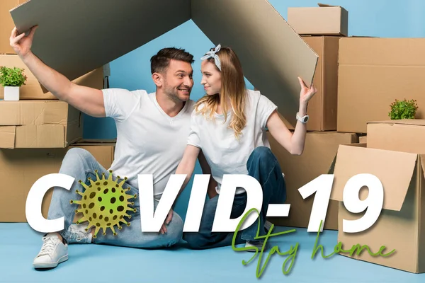 Happy Couple Holding Carton Roof Heads While Sitting Blue Cardboard — Stock Photo, Image