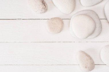 Beyaz ahşap yüzeydeki deniz taşlarının fotokopi alanı ile üst görüntüsü