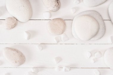 Top view of sea stones on white wooden background clipart