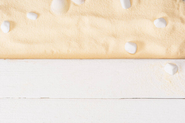 Top view of white wooden planks near sea stones on textured sand