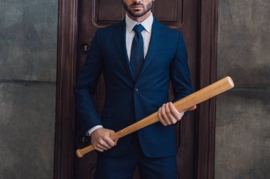 Cropped view of collector with baseball bat near door in room clipart