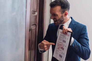 Kızgın koleksiyoncu, hacizli belgelere işaret ediyor. Kapıda yazı yazıyor ve bağırıyor.