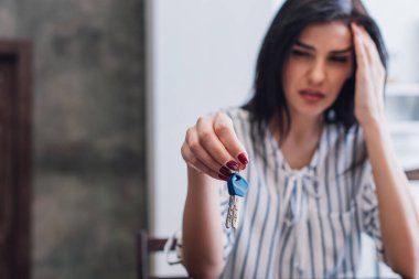 Selective focus of stressed woman showing keys in room clipart