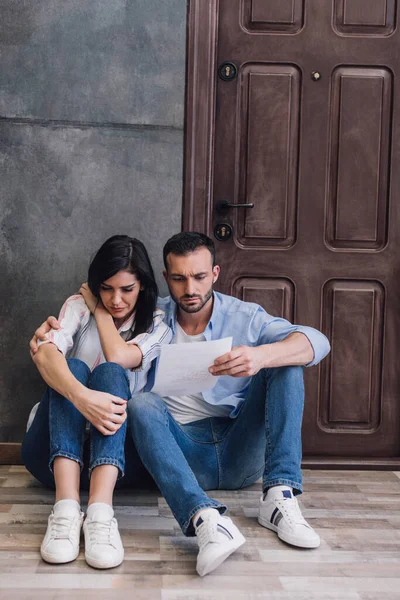 Husband Reading Document Hugging Stressed Wife Wall Floor — Stock Photo, Image