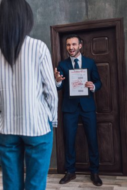 Elinde haciz belgesi olan kızgın bir koleksiyoncu ve odada bir kadının önünde bağıran son uyarı yazısı.
