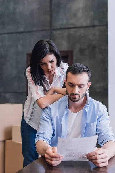 Mujer Con Brazos Cruzados Cerca Hombre Leyendo Documento Mesa Habitación — Foto de Stock