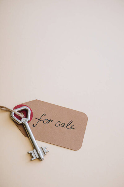 Top view of key with trinket with for sale lettering on white background