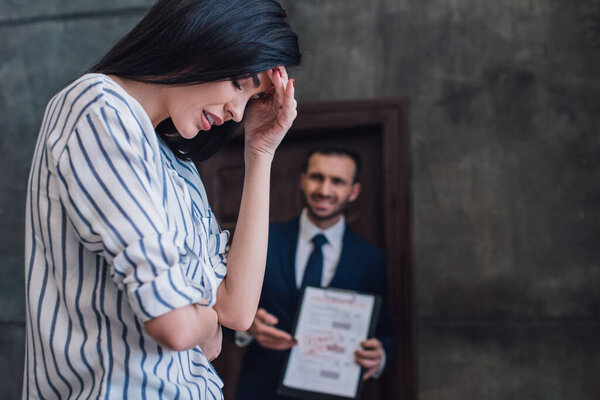 Выборочный фокус расстроенной женщины и сердитый коллекционер с документами в комнате
