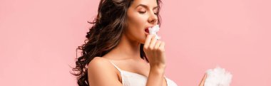 Panoramic crop of sexy girl eating cotton candy isolated on pink clipart