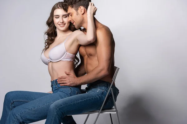 Happy Woman Bra Touching Shirtless Man Jeans Sitting Grey — Stock Photo, Image