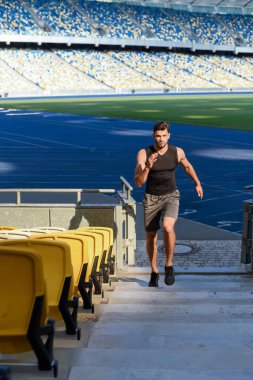 Genç sporcu stadyumun merdivenlerinde koşuyor.