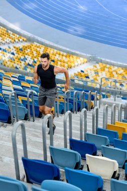 Genç sporcu stadyumun merdivenlerinde koşuyor.