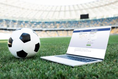 KYIV, UKRAINE - 20 Haziran 2019: Stadyumdaki çimenli futbol sahasında Facebook sitesi bulunan futbol topu ve dizüstü bilgisayar